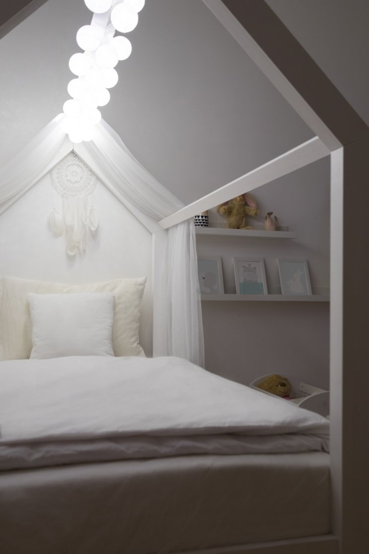 Detská posteľ v tvare domčeka v tme osvetlená len LED svetlami nad ňou