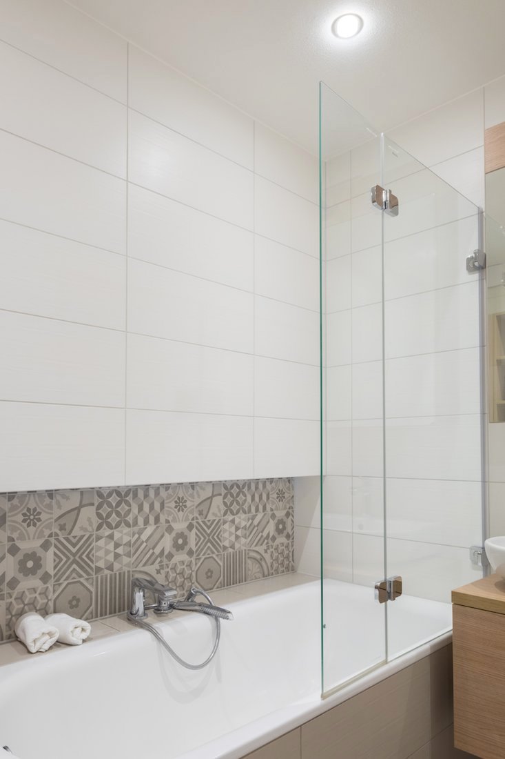 Biela kúpeľňa s vaňou a so silným osvetlením oživená mozaikou
