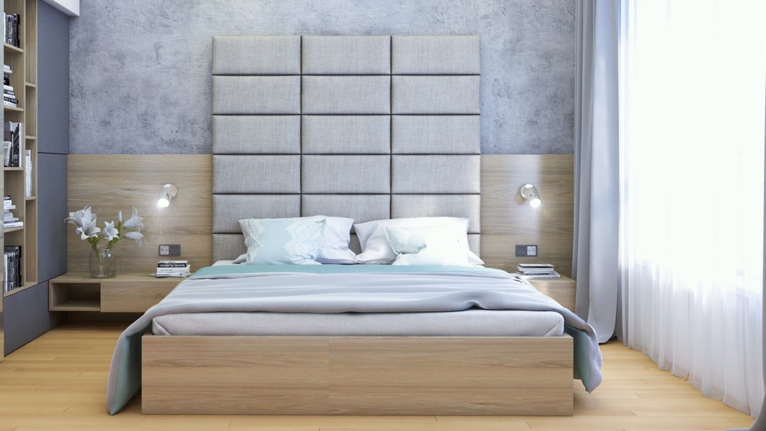Spálňa s betónovou stenou, posteľou so sivou čalúnenou zástenou a drevenými prvkami ako aj knižnicou a nočnými stolíkmi