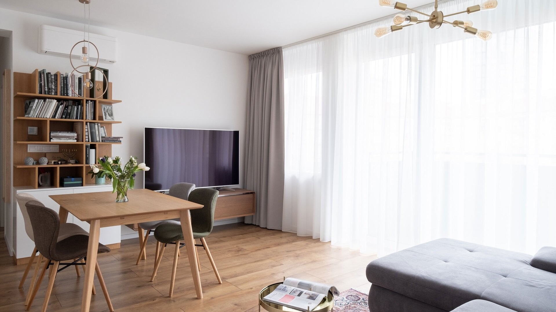 Obývačka v neutrálnych farbách obohatená zlatými prvkami a prevažne dreveným nábytkom vrátane jedálenského stola